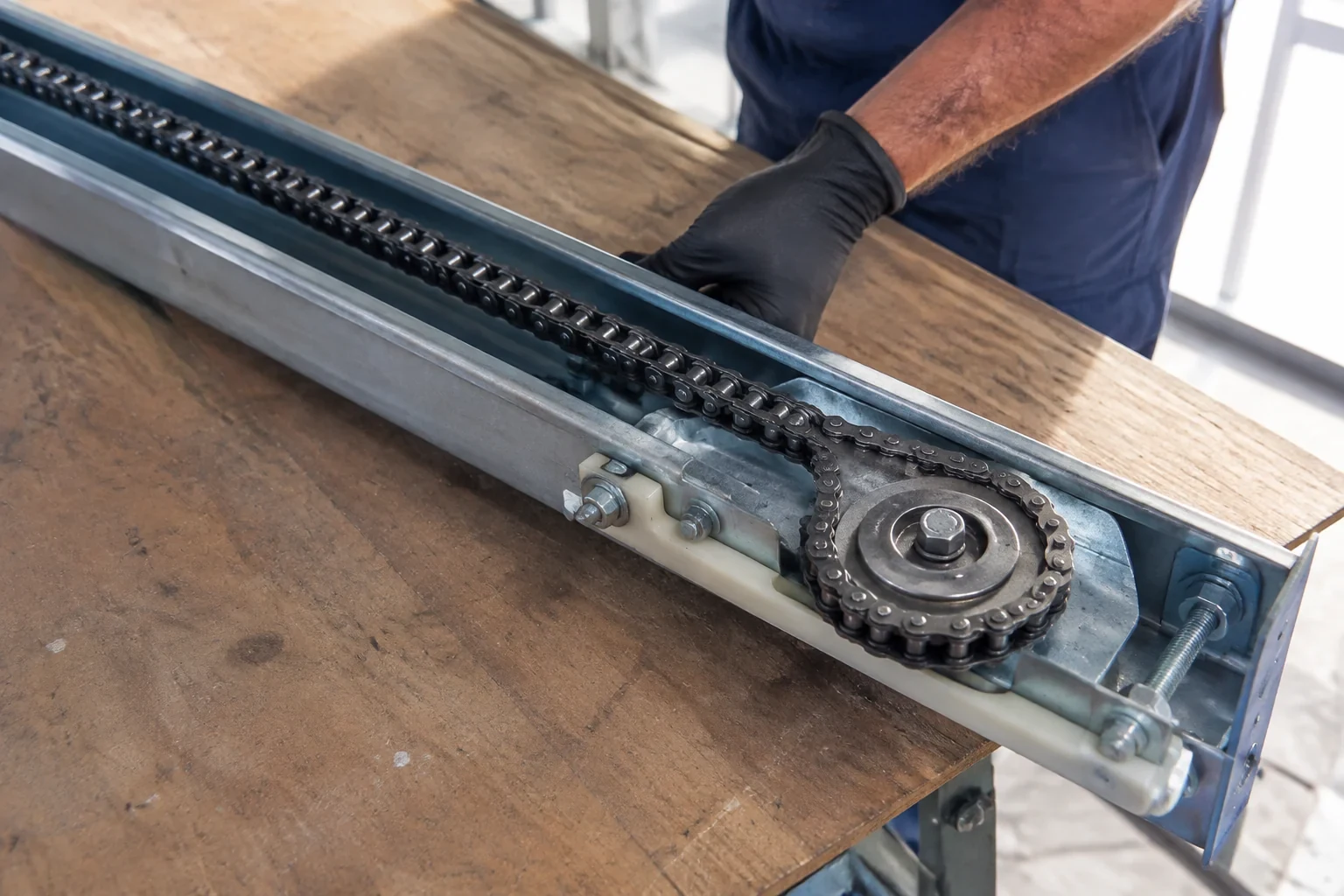 Detached opener rail with linked chain and sprocket on a workbench