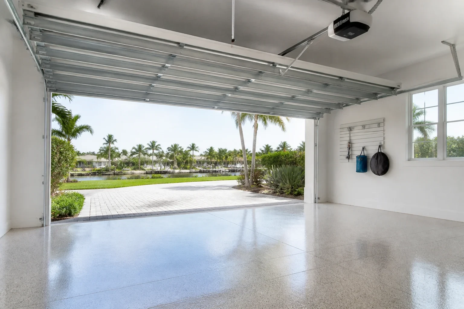 Open sectional garage door framing a palm-lined driveway